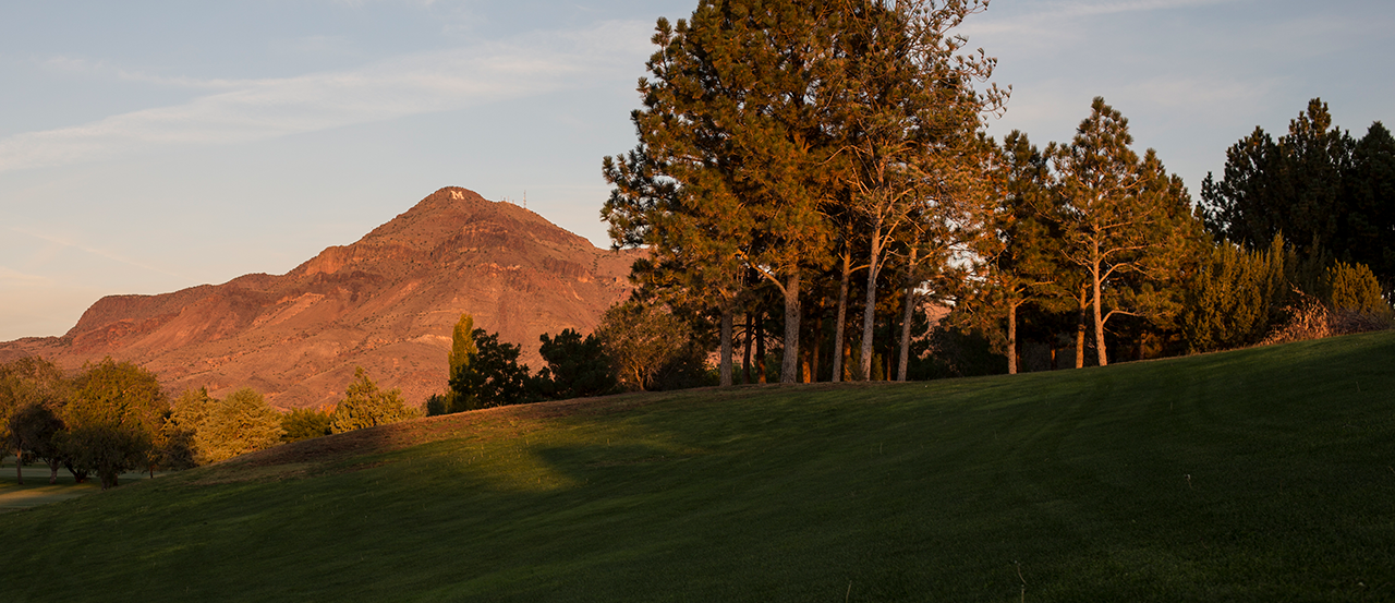 Image of M Mountain at sunrise, golf course and trees in the foreground